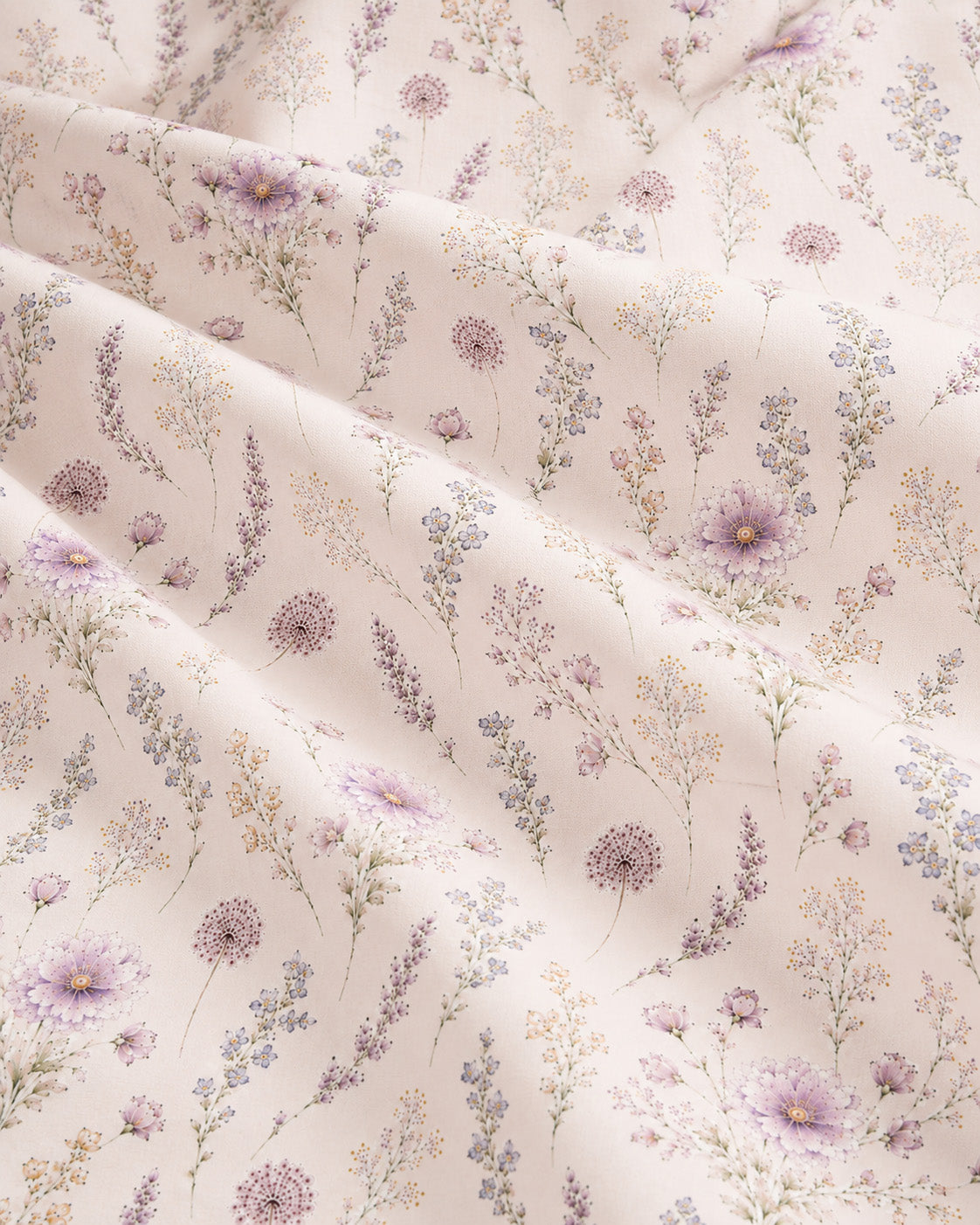 A close crop of the printed fabric falling in soft diagonal folds, showing the design at full scale - white, printed with lavender and mauve wildflowers on slender stems.