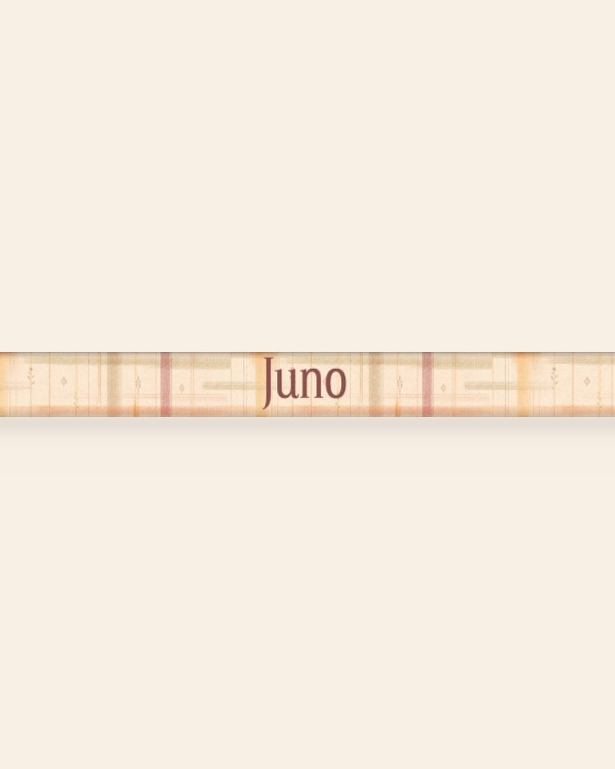 A close, straight-on crop of the leash strap laid flat on a cream background, showing the print and the sample name Juno running along the webbing. The strap is a cream plaid crossed by apricot, rose and sage lines.