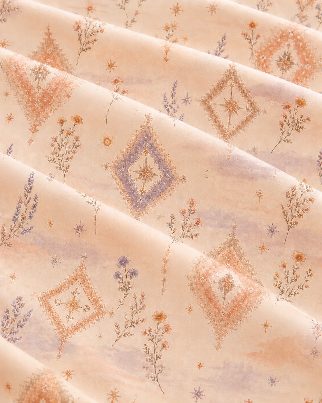A close crop of the printed fabric falling in soft diagonal folds, showing the design at full scale - a peach and apricot wash set with cream diamond medallions and fine wildflower sprigs.