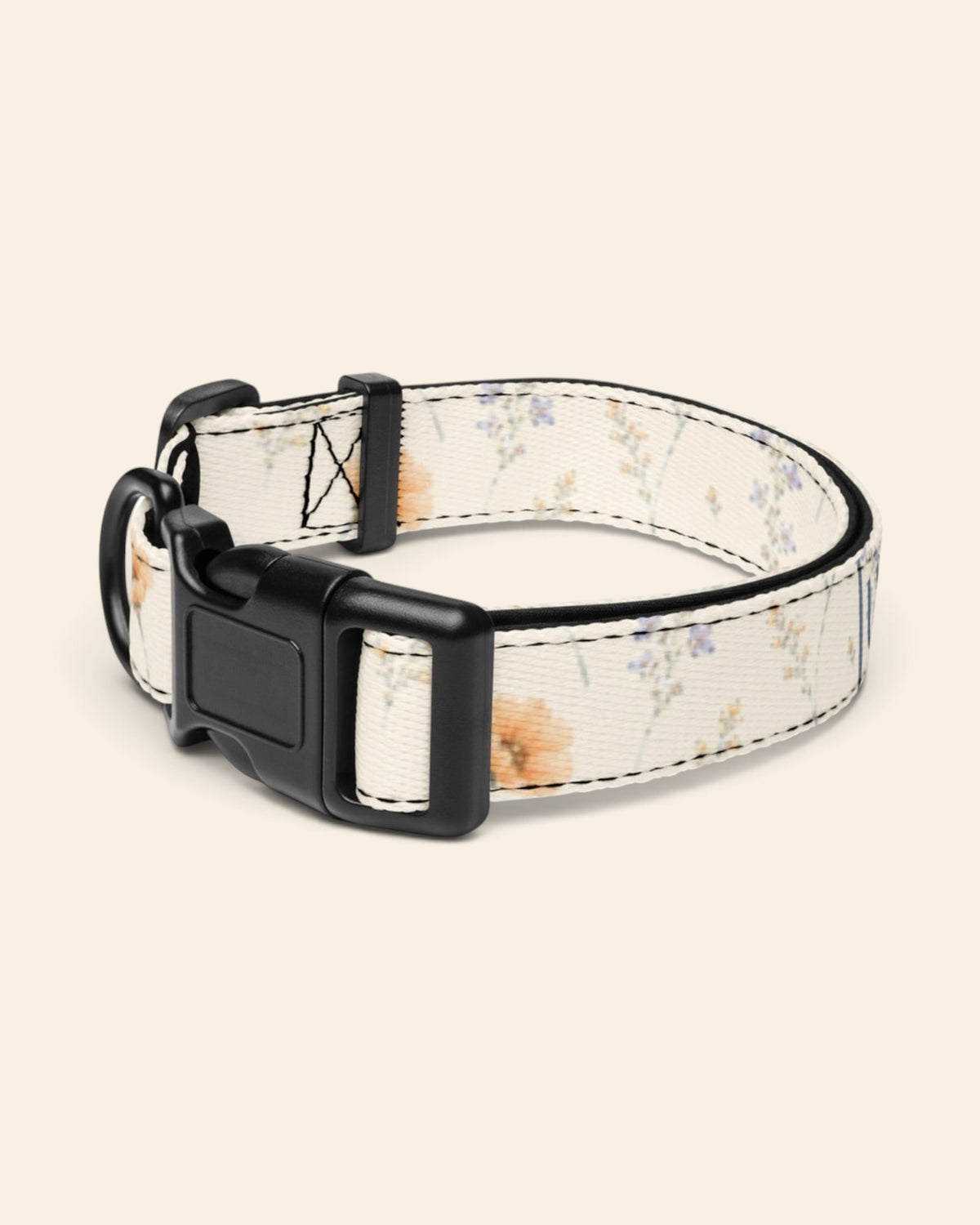The collar alone on a plain cream background with no personalisation, stood in a ring and angled to show the black side-release buckle face, the D-ring and the tri-glide slider. The webbing is white, printed with small apricot poppies and lilac and periwinkle wildflowers on fine stems.
