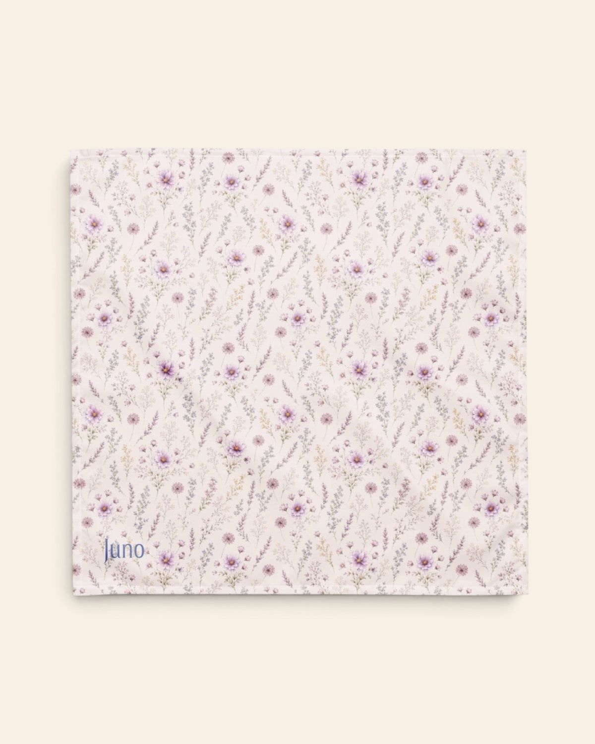 The bandana laid flat as a full square on a cream background, the print running on the diagonal. It is white, printed with lavender and mauve blooms on slender stems, with the sample name Juno printed in the lower left corner.