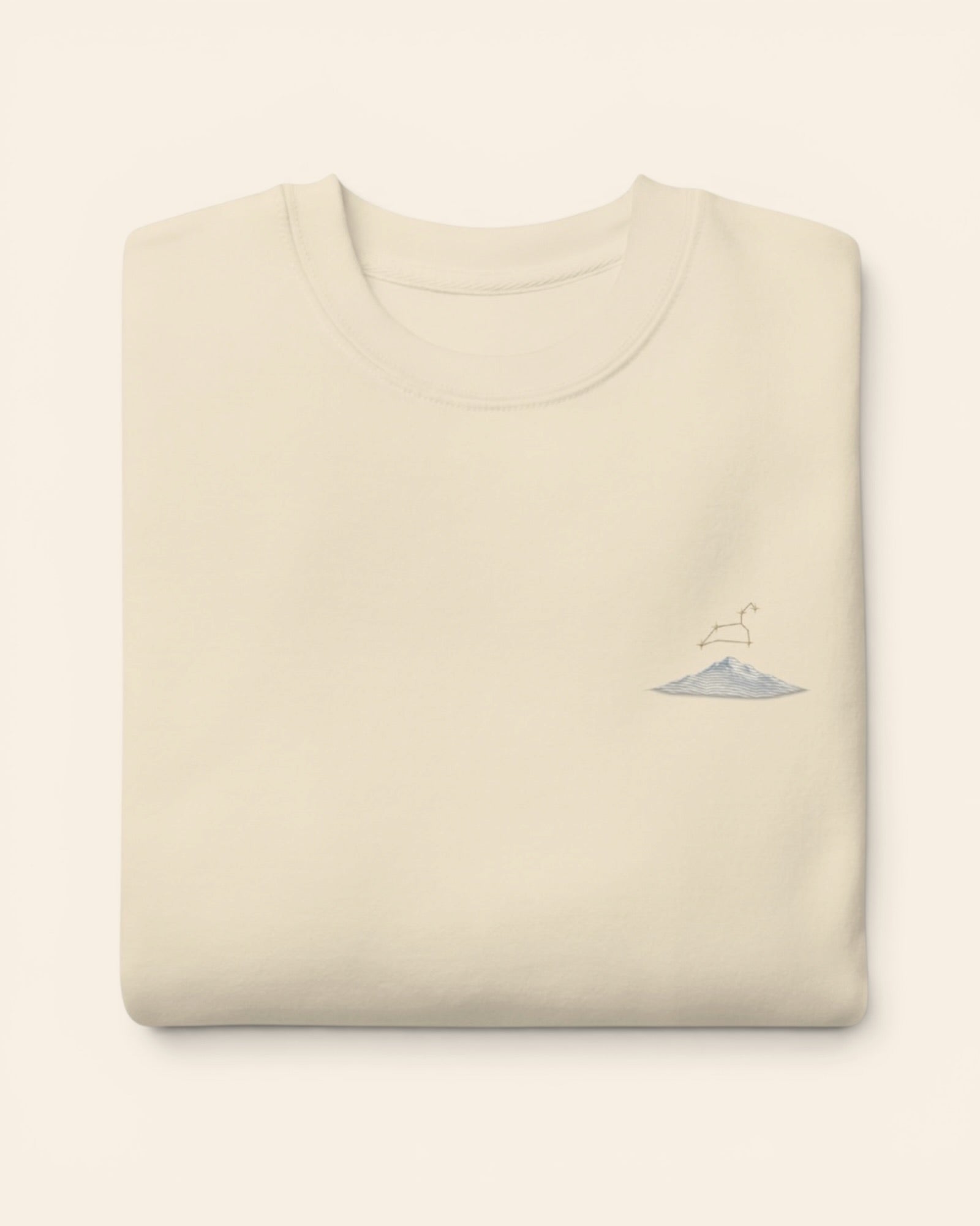 Leo constellation crewneck sweatshirt with embroidered stars above a mountain ridge, in Bone