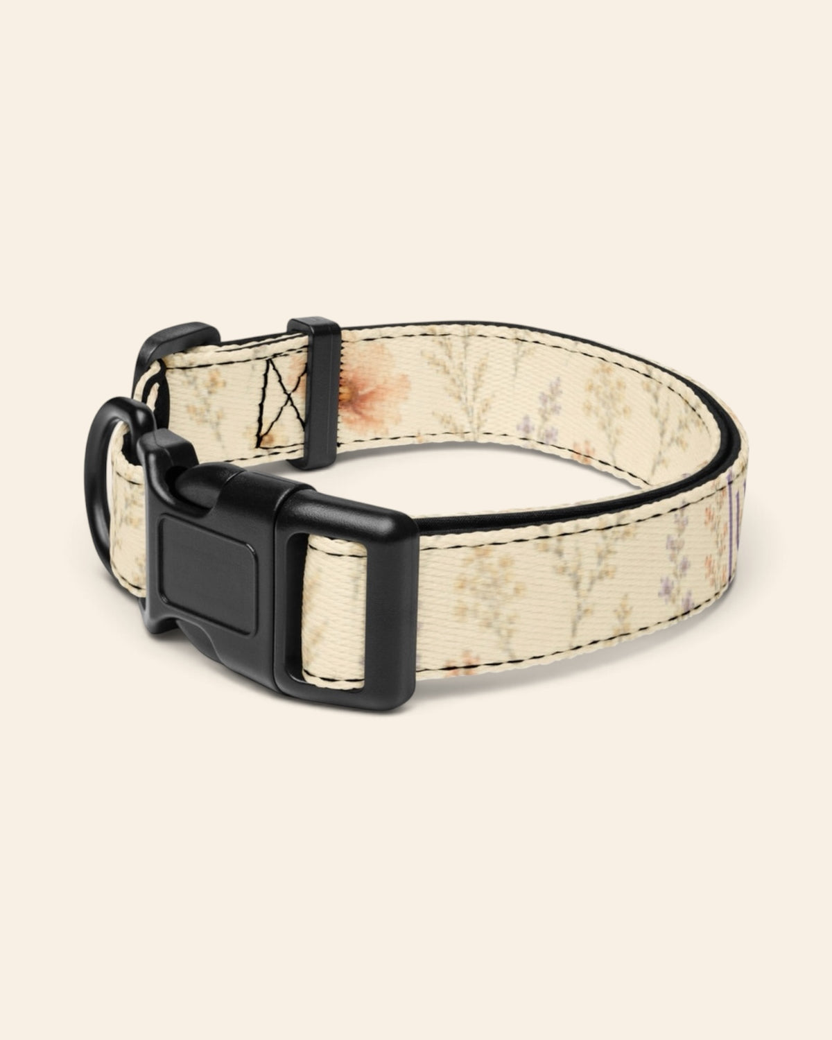 The collar alone on a plain cream background with no personalisation, stood in a ring and angled to show the black side-release buckle face, the D-ring and the tri-glide slider. The webbing is soft butter-cream, printed with small apricot and coral blooms among fine sage stems.