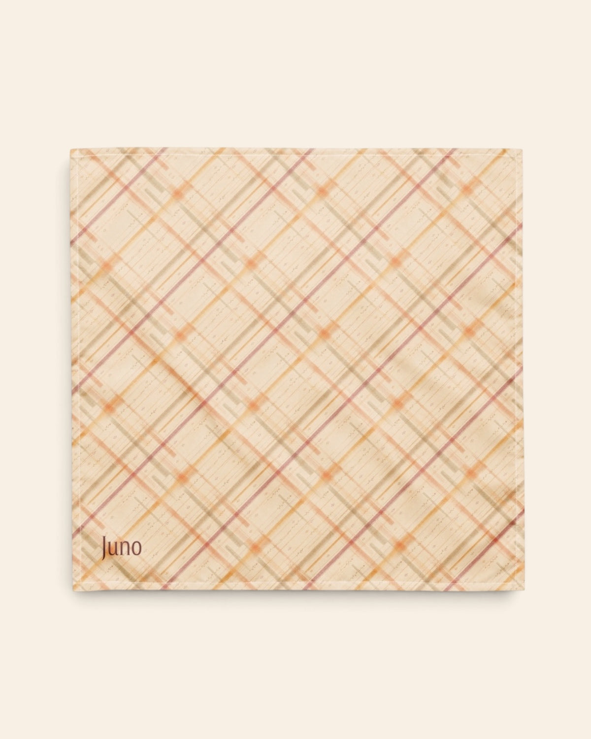The bandana laid flat as a full square on a cream background, the print running on the diagonal. It is a cream plaid crossed by apricot, rose and sage lines, with the sample name Juno printed in the lower left corner.